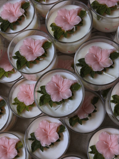 pink hibiscus in a clear mini jar with green leaves