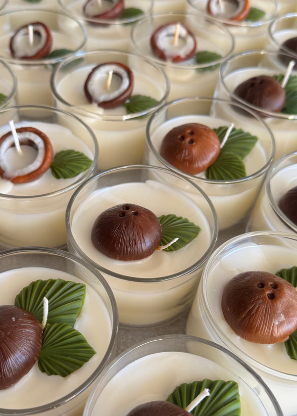 Candle with coconuts and green leaves in a clear mini jar