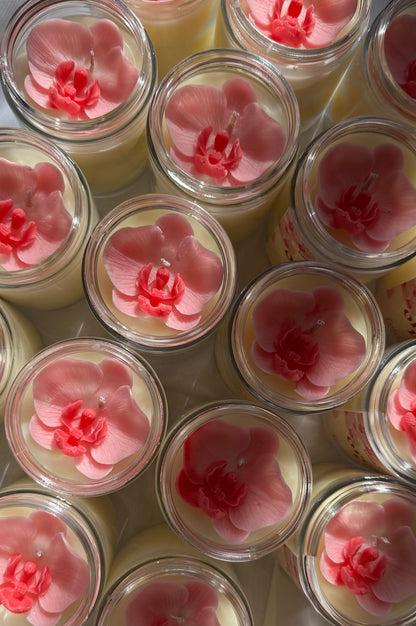 Jars of candles with pink floral orchid designs on a white background